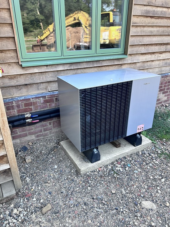 Air source heat pump installed outside a timber-clad building